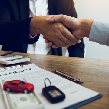 usaa extended car warranty service signing contract shaking hands contract red toy car and car keys on the table on the contract